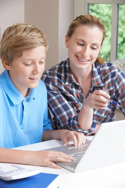 Tutor de casa feminino ajudando menino com estudos usando computador portátil — Fotografia de Stock