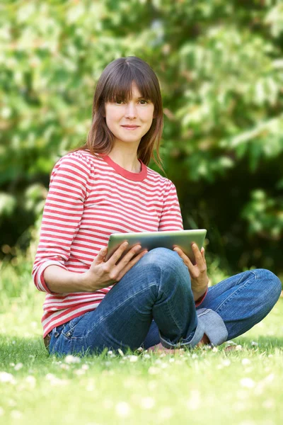 Retrato de mujer joven atractiva usando tableta digital en el parque — Foto de Stock