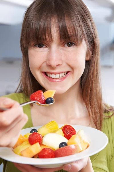 Молодая женщина ест миску свежего фруктового салата — стоковое фото