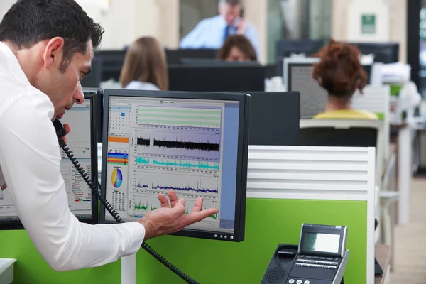 Uomo d'affari al telefono utilizzando il computer in ufficio occupato — Foto Stock