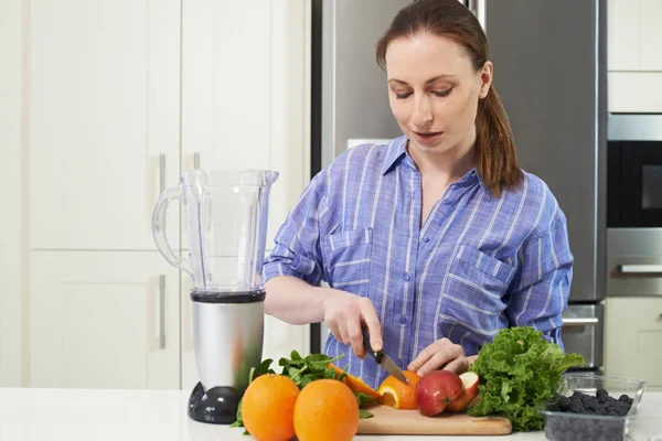Kvinna i köket hugga frukt att sätta i Juicer — Stockfoto