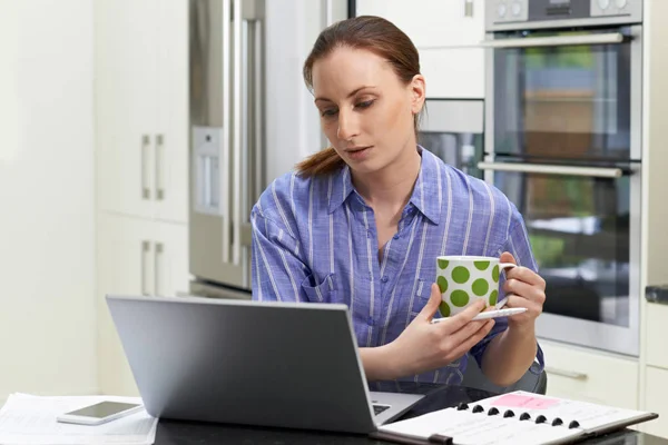 Kvinnlig frilansande arbetstagare använder Laptop och dricka kaffe i Kitc — Stockfoto