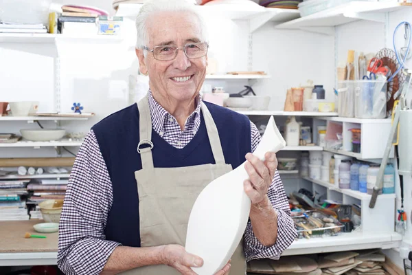 Портрет пожилого человека, держащего вазу в керамической мастерской — стоковое фото