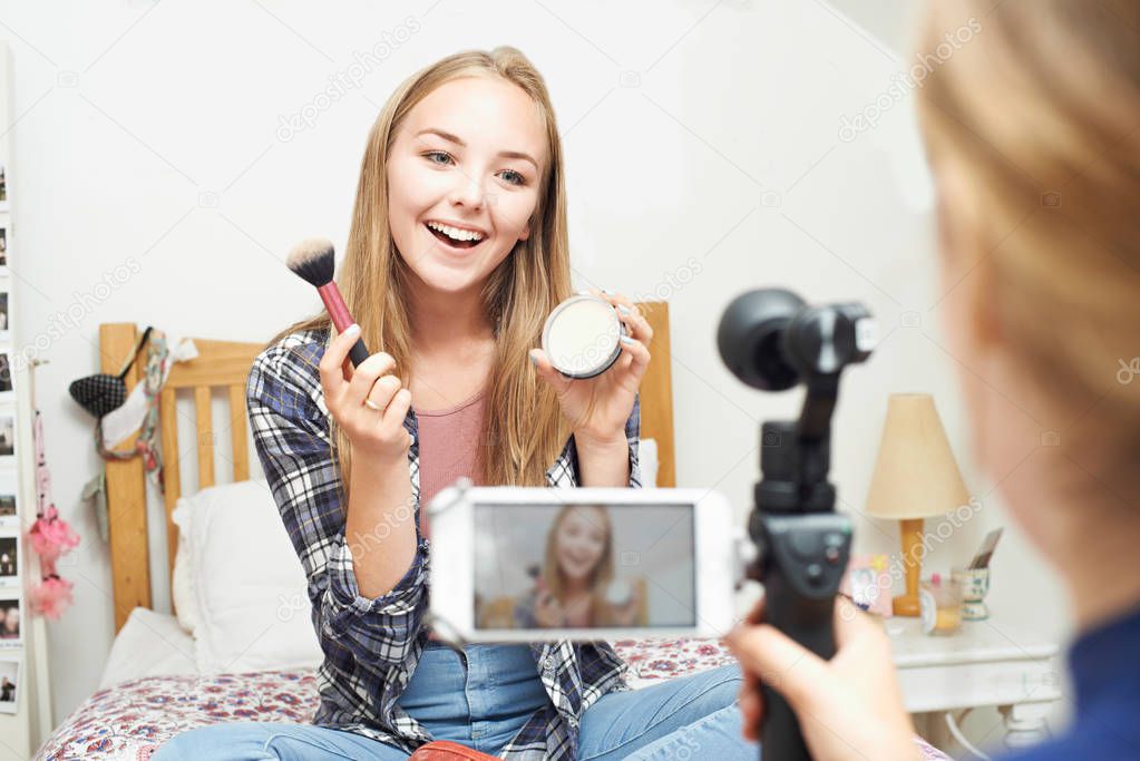 Two Teenage Girls Recording Beauty Blog In Bedroom