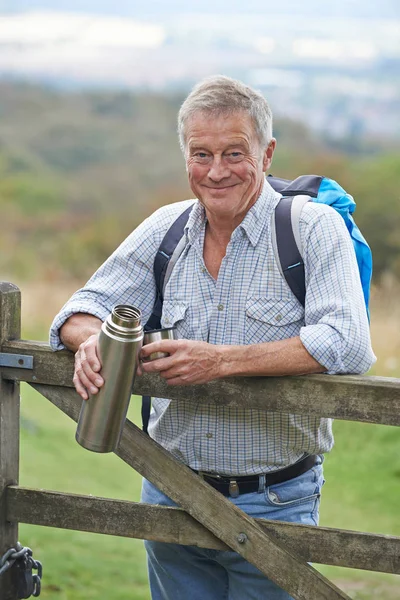 Portrait Of Senior Man On Hike In Countryside Resting By Gate An — Stock Photo, Image