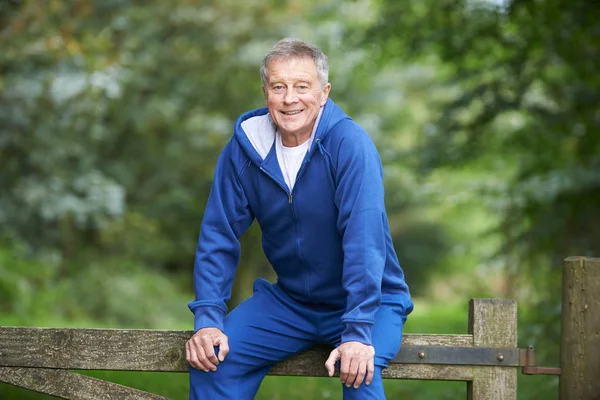 Senior Man Resting On Gate During Exercise In Countryside — Stock Photo, Image