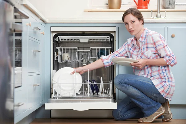 Portret van vrouw laden Dishwashwasher In keuken Stockafbeelding