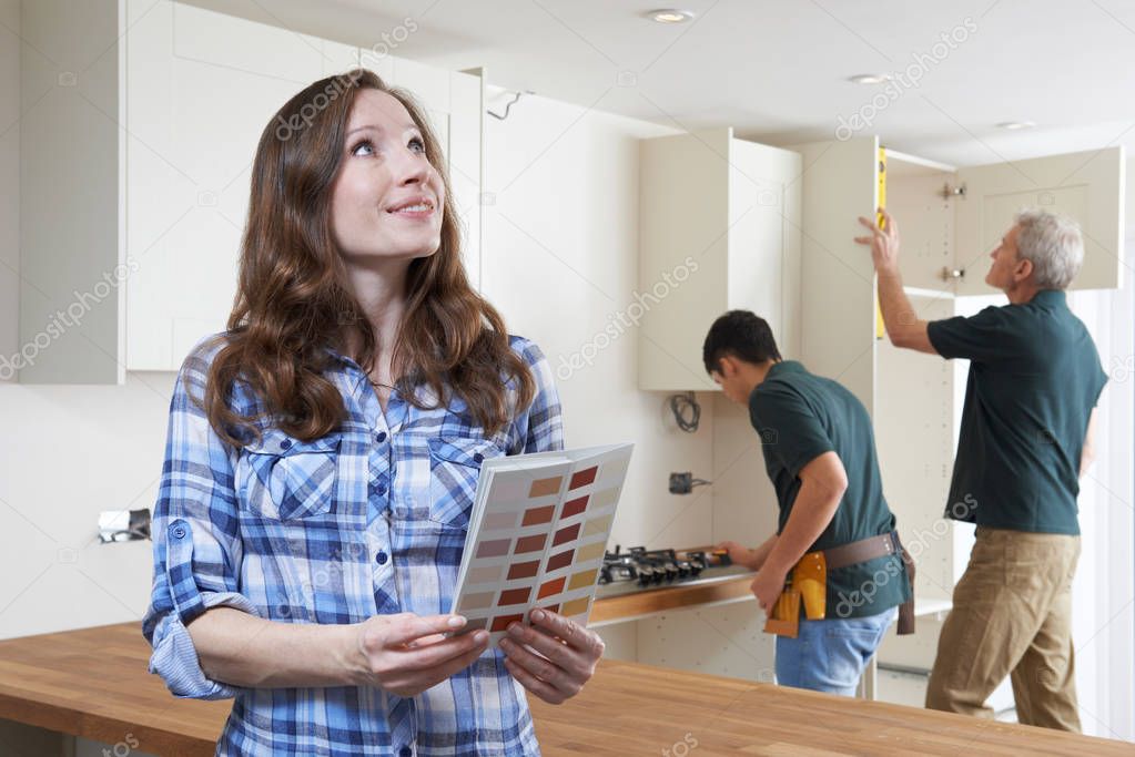 Woman Looking At Paint Chart In New Kitchen