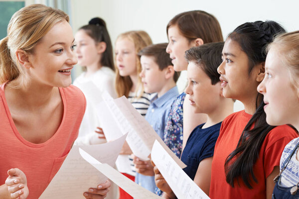 Children In School Choir Being Encouraged By Teacher