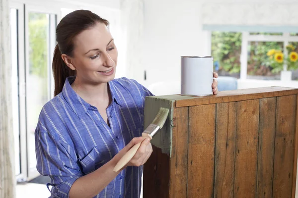 Женщина рисует старый деревянный шкаф дома — стоковое фото