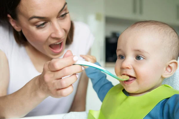 Sorrindo menino de 8 meses de idade em casa em alta cadeira sendo alimentado Sol — Fotografia de Stock