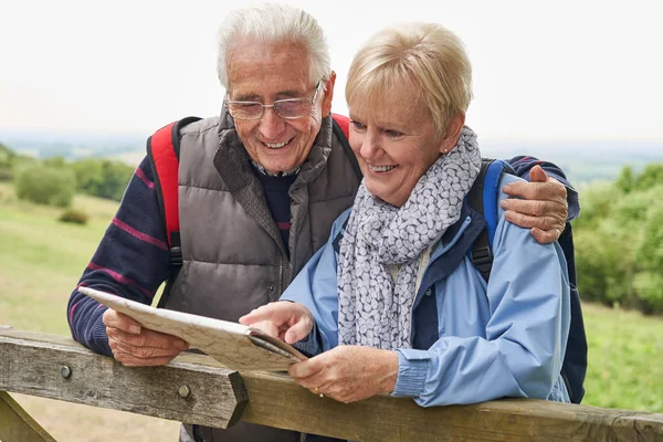Retired Couple On Walking Holiday Resting On Gate With Map — Stock Photo, Image