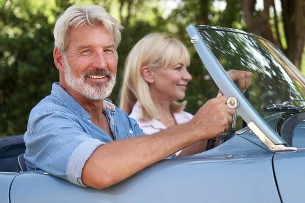 Зрелая пара наслаждается поездкой на классическом спортивном автомобиле — стоковое фото
