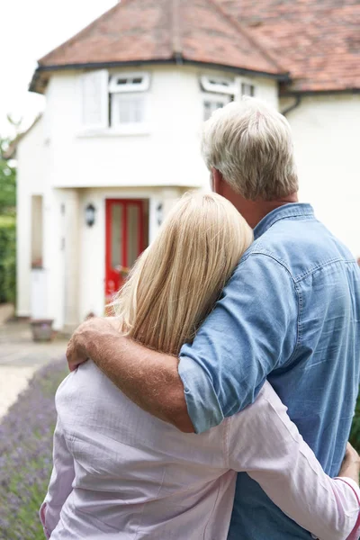 Rückansicht eines reifen Paares, das im Garten steht, Blick auf sein Traumhaus — Stockfoto