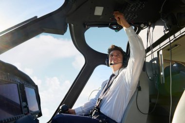 Helikopterin kokpitinde erkek pilot kalkıştan önce uçuş öncesi kontrol yapıyor.