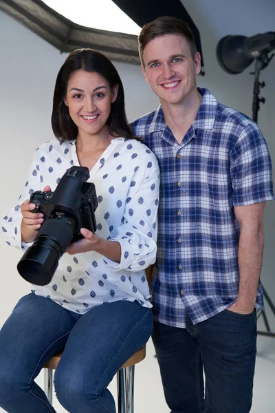 Portrait Of Male And Female Photographers In Studio For Photo Shoot With Camera And Lighting Equipment