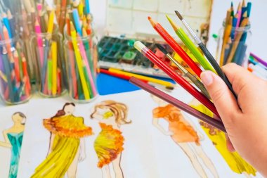 Çizimin arka planına çizimler çizmek için sanat araçları ile el.