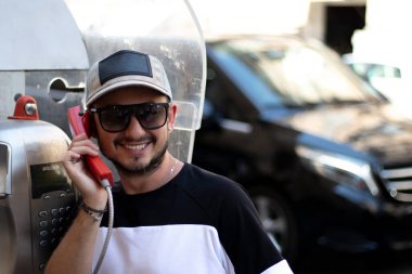 Şehir telefonunda gülümseyen genç bir adam.