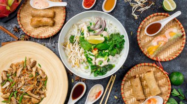 Assorted asian dinner, vietnamese food. Pho ga, pho bo, noodles, spring rolls top view clipart