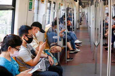 Bangkok, Tayland 25 Mart 2020. BTS trenindeki yolcular kendilerini Covid-19 'dan korumak için maske takarlar. Demiryolu departmanı tüm demiryolu yolcularının yüz maskesi takmasını ve yolculuk sırasında birbirleri arasında yeterli alan bırakmasını şart koşuyor.