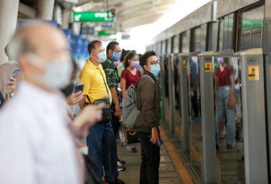 Bangkok, Tayland 25 Mart 2020. BTS istasyonundaki yolcular kendilerini Covid-19 'dan korumak için maske takarlar. Bir trende veya istasyonda yolculuk ederken, aranıza mesafe koyarsınız..