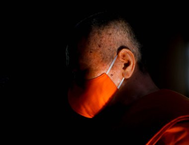 Bangkok, Tayland 25 Mart 2020 'de, yüzü maskeli bir Taylandlı keşiş COVID-19' un yayılmasını engellemek amacıyla Wat Traimit Tapınağı 'nda (Altın Buda Tapınağı) yayılan veba karşıtı bir duaya katılmaya hazırlanıyor.