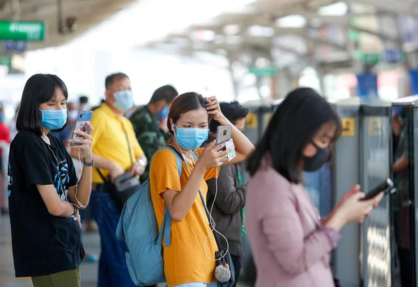 Bangkok, Tayland 25 Mart 2020. BTS istasyonundaki yolcular kendilerini Covid-19 'dan korumak için maske takarlar. Bir trende veya istasyonda yolculuk ederken, aranıza mesafe koyarsınız..