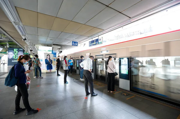 Bangkok, Tayland 25 Mart 2020. BTS istasyonundaki yolcular kendilerini Covid-19 'dan korumak için maske takarlar. Bir trende veya istasyonda yolculuk ederken, aranıza mesafe koyarsınız..