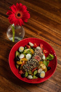 Tahta bir masanın tepesinde yemek olan kırmızı bir tabak.