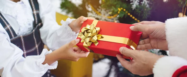 Close up with a hand holding red gift box with gold ribbon tied as a gift for the family On occasion of Christmas, Happy New Year or around birthdays Is a symbol instead of thank Good friendship