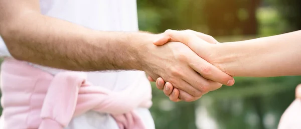 Beyaz spor kıyafetleri giymiş, şehirdeki bir parkta duran sporcu bir arkadaşıyla tokalaşmak üzere olan bir erkek sporcunun elini yakın plan çekiyoruz. Sağlığınıza dikkat etmeyi kabul edin. Boşluğu kopyala
