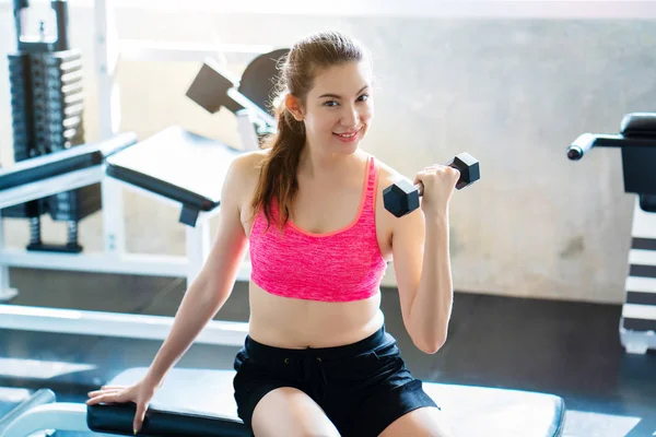 Asian women lifting dumbbell workout in a Fitness center or gym. Exercise helps to have a healthy body and beautiful muscles. And without the disease. Concept of health care and playing sports