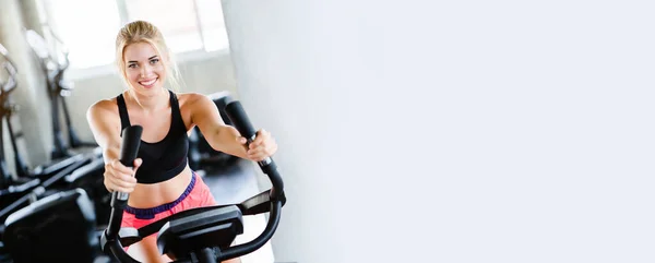 Spor kıyafetleri giyen kadınlar spor yapıyor, spor salonunda elektrikli bisiklet çeviriyor sağlık için güzel bir şekle sahip oluyorlar ve kasların gevşemesini sağlıyorlar. afiş arkaplanına boşluk kopyala.