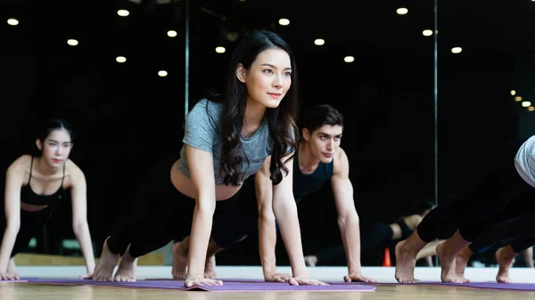 Bir grup Asyalı kadın spor salonunda yoga dersleri alıyor, spor kıyafetleri giyiyorlar, ve egzersiz sağlıklı bir vücuda, iyi bir şekle, gevşemiş kaslara ve kaslı bir vücuda sahip olmaya yardımcı oluyor. Spor ve sağlık konsepti