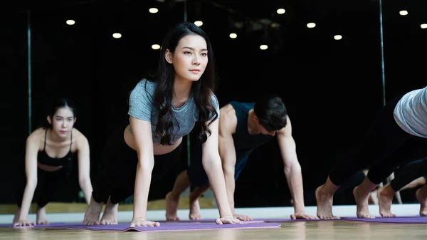 Bir grup Asyalı kadın spor salonunda yoga dersleri alıyor, spor kıyafetleri giyiyorlar, ve egzersiz sağlıklı bir vücuda, iyi bir şekle, gevşemiş kaslara ve kaslı bir vücuda sahip olmaya yardımcı oluyor. Spor ve sağlık konsepti