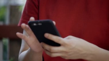 Asyalı bir kadın mutlu bir gülümseme evdeki bahçede akıllı telefon kullanıyor. Ürün sipariş etmek için çevrimiçi başvuru yoluyla sipariş vermek. Ya da 5G teknolojisi olan müşterilerle ya da arkadaşlarla konuş. Kavram teknolojisi