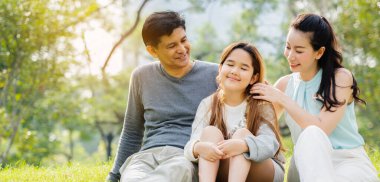 Asyalı aileler piknik yapmaktan mutlu olurlar. Parkta ebeveynlerin ve kızların faaliyetlerini yaparlar. Uzun yaz tatillerinde doğa hakkında iyi havayla bilgi edinin. Konsept Sağlık Sigortası COVID-19