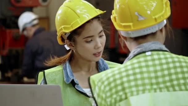 Femme ingénieur asiatique debout et parler avec des collègues. Utilisez l'ordinateur portable lors d'une réunion d'usine. Portez un casque pour la sécurité pendant le travail. Parler de distance sociale pour prévenir l'infection par le coronavirus (COVID-19) 