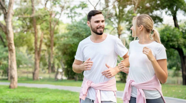 Beyaz çiftler dışarıda egzersiz yapıyor ya da sabah park ediyorlar. Günlük egzersiz vücudunu sağlıklı tutar. Modern insanların yeni normal tarzında bir yaşam tarzı. Sosyal Mesafeyi Kabul Et.