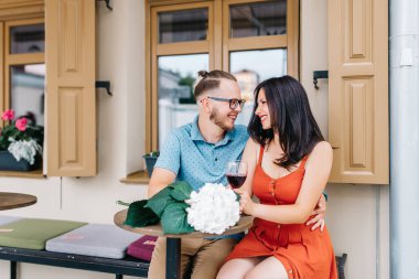 Restoran konseptinde sevgililer günü şenliği. Gülümse, yetişkin sevgili çift ve erkek el ele bir şarap tutun. Bir fısıltı gibi konuşuyorlar. Restoranda romantik bir akşam yemeği.