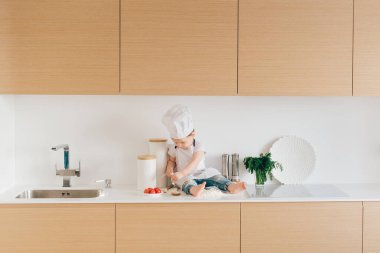 Küçük aşçı şık mutfakta pizza pişiriyor. Evde kalır, eğlenir ve bütün aileyle pizza pişiririz.