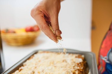 Aşçı tabağın üzerine rendelenmiş peynir serpti. Evde kalıp lazanya pişiriyoruz..