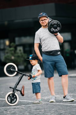 Oğlu ve babası eğleniyor ve eğleniyorlar. Segway ve pist üzerinde gidiyoruz. Şehirde şık bir aile.