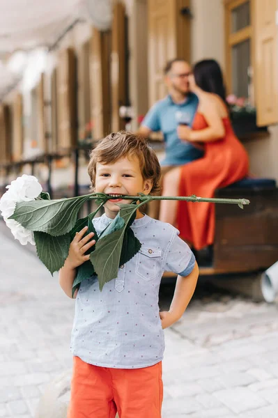 Sommarsemester med familjen. En liten pojke i förgrunden har roligt och håller en hortensia blomma i tänderna. — Stockfoto