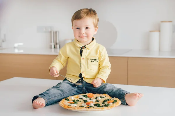 El cocinero está comiendo pizza en la cocina. Nos quedamos en casa, nos divertimos y comemos pizza con toda la familia. . — Foto de Stock