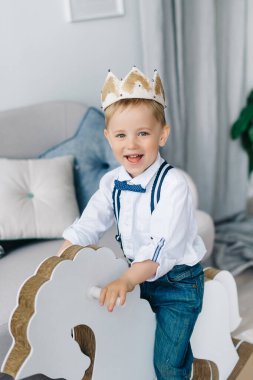 Taçlı bir çocuk, koronavirüs değil, prens gibi ata binen mutlu bir çocuk, evde kalmak için yaratıcılık ve gelişme kavramı.