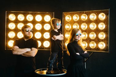 Rock yıldızı ailesi. Siyah elbiseli, güneş ışığında gözlüklü şık bir aile. Rock-n-roll müzik aile hikayesi