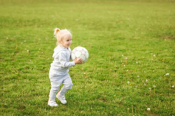 Summer walk, children on nature. Sport family. A little girl play soccer with a ball