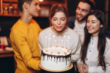 Onun için sürpriz. Bir grup mutlu insan doğum günü partisini arkadaşlarıyla kutluyor ve parti sırasında gülümsüyor. Elinde pastayla gülümseyen çekici kız.