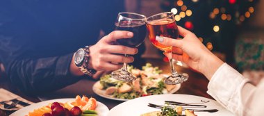 Erkekler ve kadınlar kırmızı ve beyaz şarap içerler. Gözlüklü ellerin kaybolması. Yeni yılı kutluyorlar..